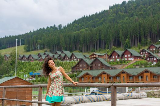 A beautiful slim girl posing next to mountain ski resort in the summer day.