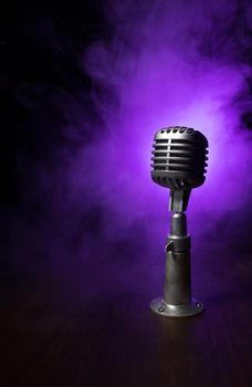 Retro style microphone on background with backlight. Vintage silver Microphone for sound, music, karaoke. Speech broadcast equipment. Live pop, rock musical performance. Selective focus