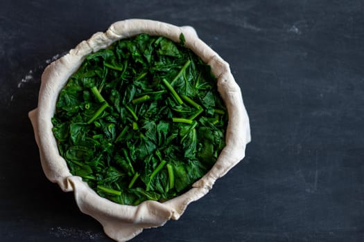 raw spinach pie preparation Standing wooden table background Copy space for text