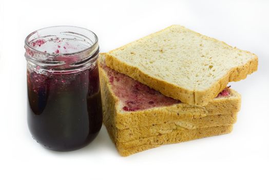 Whole wheat bread stack with grape jam on isolated white background.