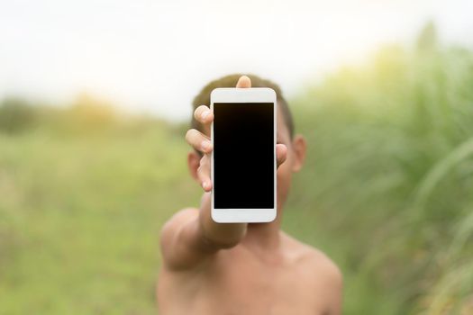 The boy stand up and show mobile phone.