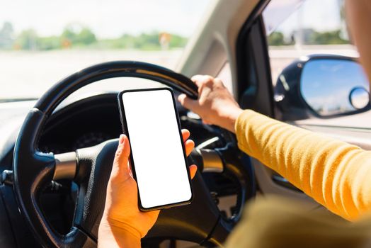 Asian woman inside a car and using a hand holding mobile smartphone blank screen while driving the car in the morning during going to work on highway, Transportation and vehicle concept