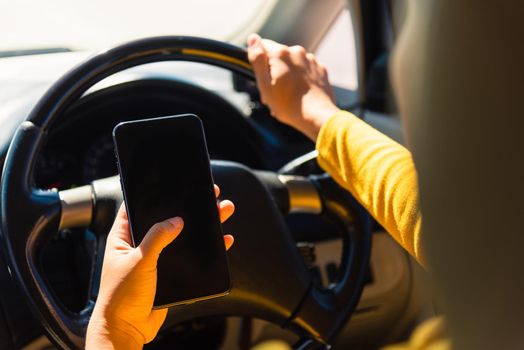 Asian woman inside a car and using a hand holding mobile smartphone blank screen while driving the car in the morning during going to work on highway, Transportation and vehicle concept