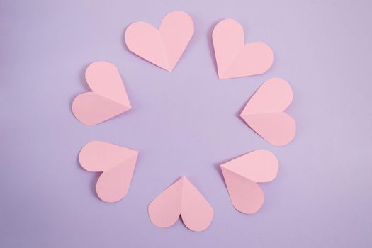 Valentine's day background. Pink hearts laid out in a circle on a pastel purple background. Valentine's day concept. Layout for postcards and congratulations. Flat lay, top view, copy space