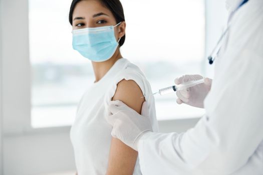 female patient in medical mask and doctor syringe injection vaccination against infection. High quality photo