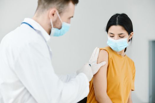 caring doctor injects covid-19 vaccine into female patient's shoulder. High quality photo