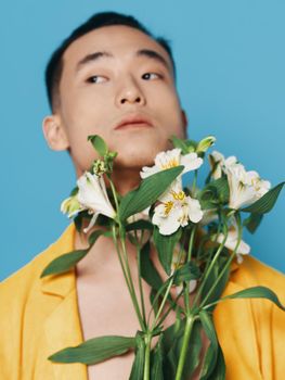 romantic asian guy with a bouquet of white flowers and in a yellow coat portrait model. High quality photo