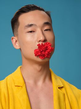 handsome asian man with a flower in his teeth yellow jacket blue background portrait. High quality photo