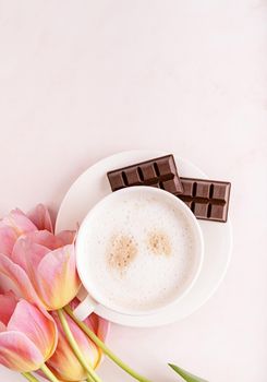 Cup of cappuccino and pink tulips top view on marble background