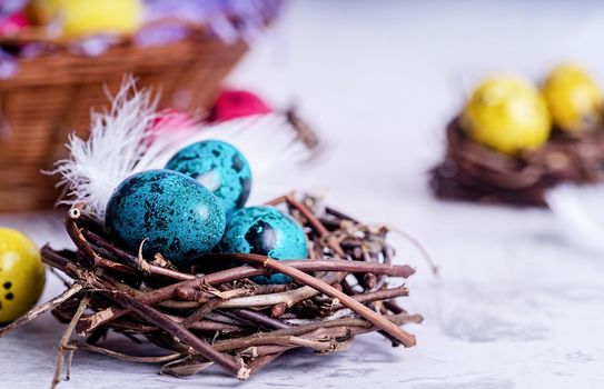 Easter holiday concept. Colored Easter quail eggs in a nest on gray marble background