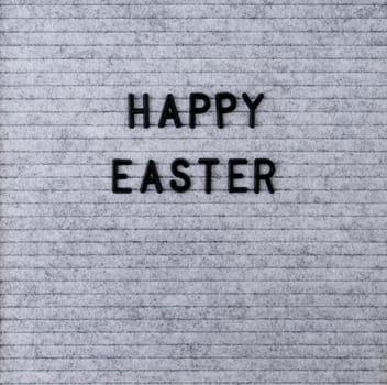 Easter holiday concept. The words Happy Easter on the grey felt letter board