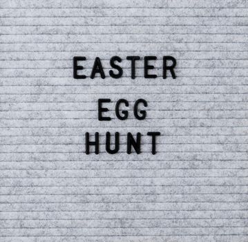 Easter holiday concept. The words Easter Egg Hunt on the grey felt letter board