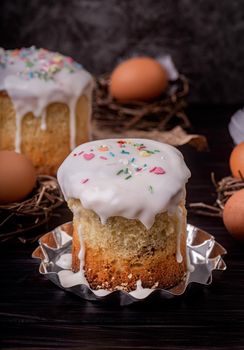 Easter holiday concept. Homemade Easter cake with white icing decorated with eggs on dark background