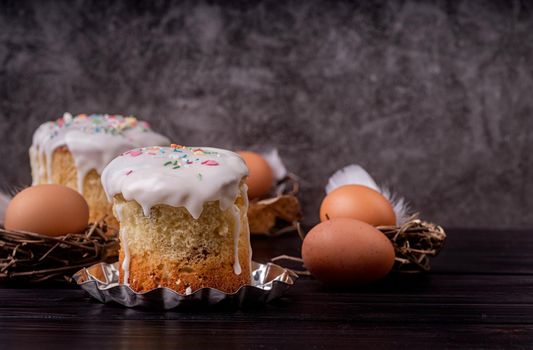 Easter holiday concept. Homemade Easter cake with white icing decorated with eggs on dark background with copy space