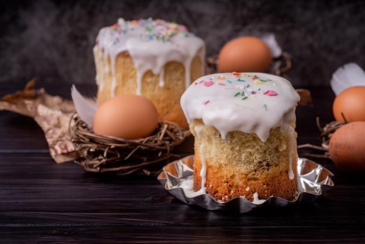 Easter holiday concept. Homemade Easter cake with white icing decorated with eggs on dark background