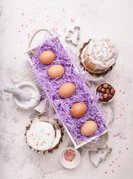 Easter concept. Baking and cooking. Easter eggs in a white wooden box decorated with glazed cakes and cooking utensils