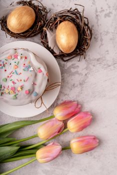 Easter concept. Glazed Easter cake with tulips and colored eggs top view flat lay