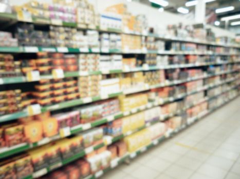 Blurred supermarket aisle with colorful food shelves of merchandise. Perspective view of abstract supermarket aisle with copy space in center, can use as background or retail concept