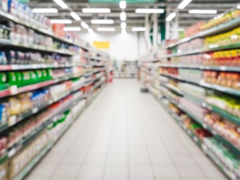 Blurred supermarket aisle with colorful shelves of merchandise. Perspective view of abstract supermarket aisle with copy space in center, can use as background or retail concept