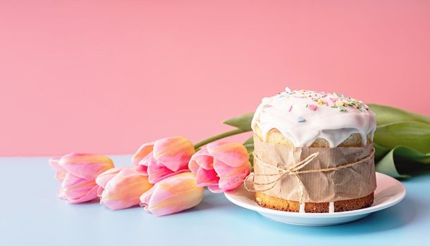 Easter concept. Easter cake with tulips on pink and blue background front view with copy space