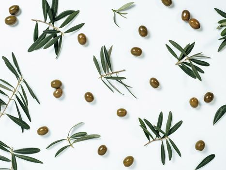 Beautiful pattern with green olives and olives tree leaves and branches on white background. Olive tree fruits and branches as pattern, top view or flat lay.