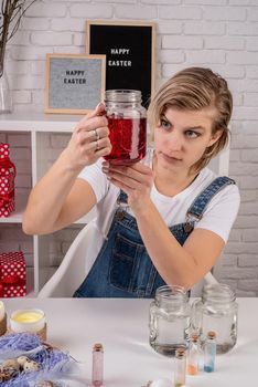 Easter concept. Woman coloring eggs at home. Young woman looking at the mason jar ready for coloring eggs front view