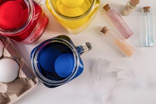 Easter holiday concept. Eggs coloring. Three mason jars with colorful eggs inside on the table