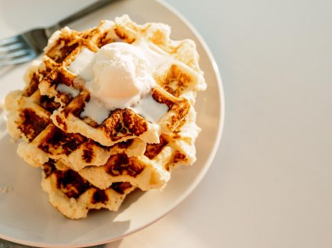 Ricotta cheese chaffles for keto diet. Stack of ricotta and lemon belgian waffles decorated with ice cream scoop.Copy space for text or design. Natural sunset or sunrise daylight. Top view or flat lay