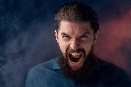 Emotional bearded man angry look shirt smoke in the background. High quality photo