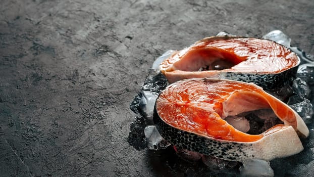 Two raw wild salmon steaks on ice over black textured background. Salmon steaks with copy space left. Horizontal banner