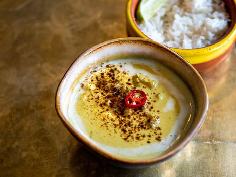 Yellow curry with cauliflower and chickpea and rice on metal tabletop background. Indian food. Vegetarian curry with copy space for text or design