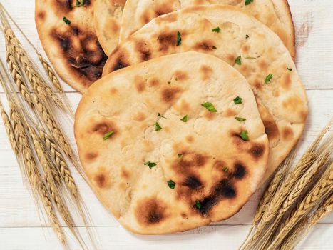 Fresh naan bread on white wooden background with copy space. Top view of several perfect naan flatbreads on metal tray