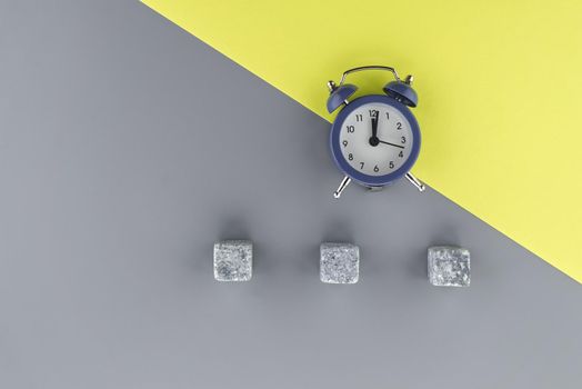 Alarm clock on a two tone grey and yellow background with copy space viewed as a flat lay. Renovation and color trends concept