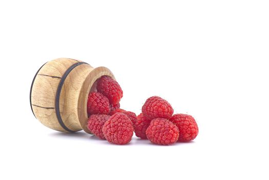 Fresh ripe raspberry spilled from a wooden pot isolated on white background