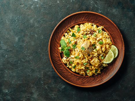 Pakistani food - biryani rice with chicken on plate. Delicious hyberabadi chicken biryani on dark background. Top view or flat lay. Copy space for text or design