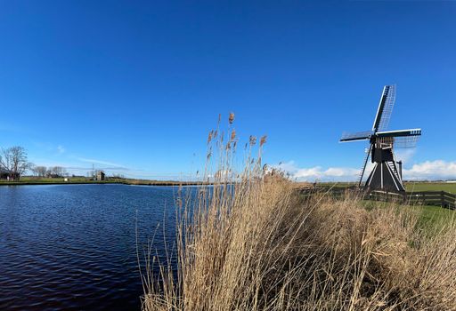 Windmill next to a canal on a winter day around Akkrum in Friesland The Netherlands