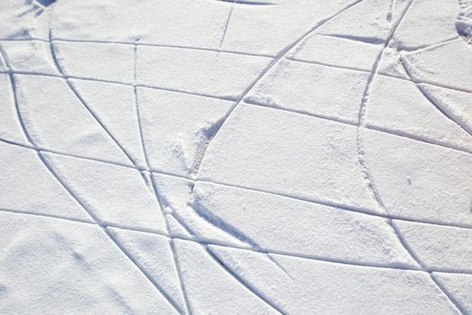 Skate tracks on ice with snowy snow. Winter background.
