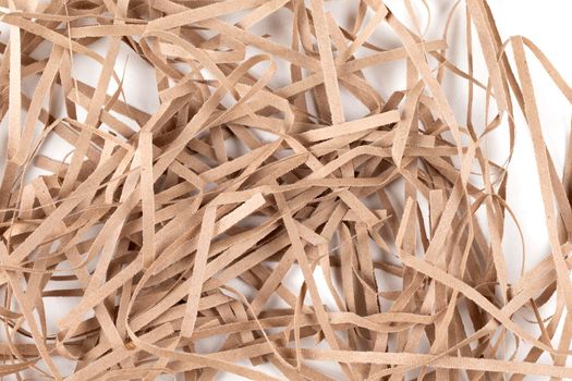 Lots of thin strips of beige paper. Decorative pieces of paper for gifts on a white background