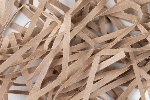 Lots of thin strips of beige paper. Decorative pieces of paper for gifts on a white background