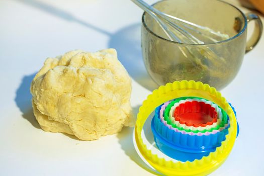 On the table is a baking dough cookie pan and a whisk. Cookies making process.