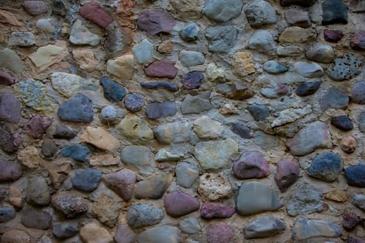 Background wall from large multi-colored stones boulders.