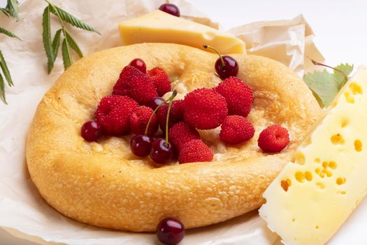 Lavash with red berries and a piece of cheese. Baked round bun for breakfast.