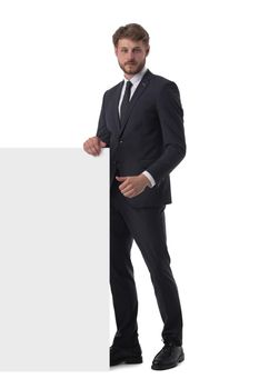 Full length portrait of young man in suit showing banner whiteboard sign isolated on white background