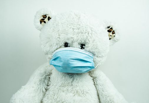 Masked teddy bear with surgical mask on white background