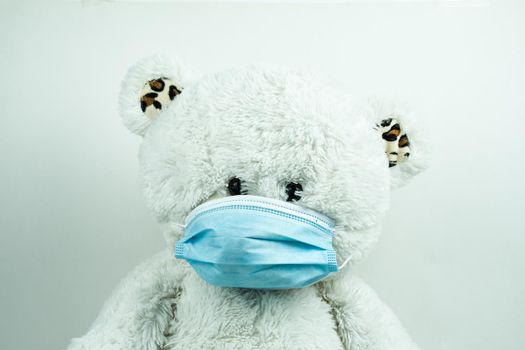 Masked teddy bear with surgical mask on white background