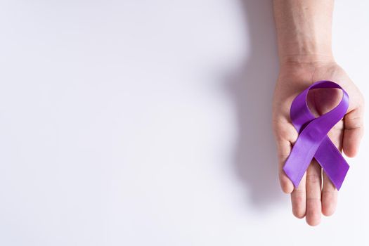 World cancer day, hands holding purple ribbon on grey background with copy space for text. Healthcare and medical concept.