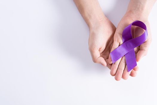 World cancer day, hands holding purple ribbon on grey background with copy space for text. Healthcare and medical concept.