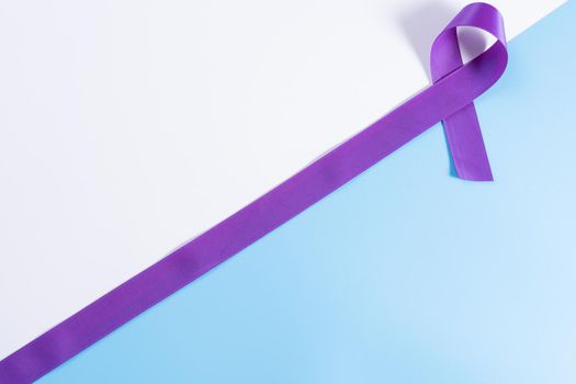 World cancer day, purple ribbon on with and blue background with copy space for text. Healthcare and medical concept.
