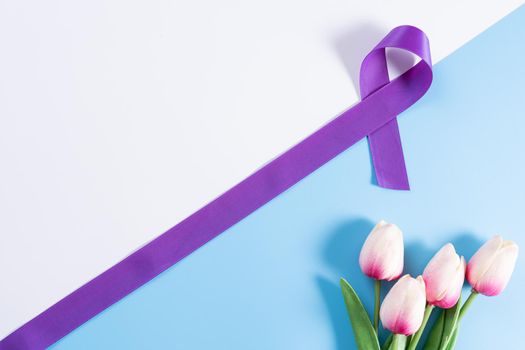 World cancer day, purple ribbon and tulip flower on with and blue background with copy space for text. Healthcare and medical concept.