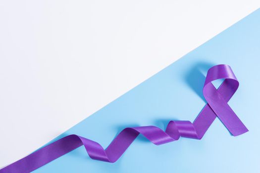 World cancer day, purple ribbon on with and blue background with copy space for text. Healthcare and medical concept.